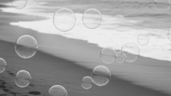 Clear bubbles float over a serene black-and-white beach scene with gentle waves lapping at the shore.